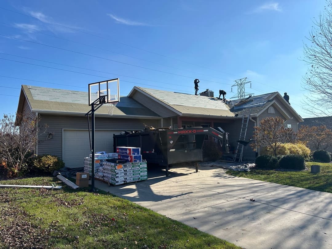 Roofing project in progress on a suburban home, with workers and construction materials visible.